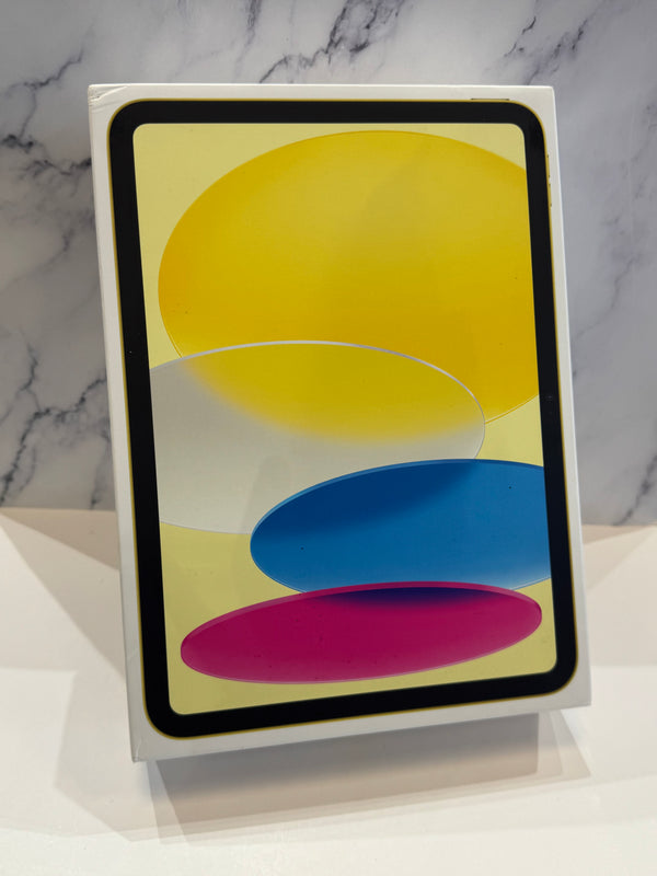 A tablet in its white retail box, showing a colorful abstract screen design with yellow, blue, and pink shapes, set against a white surface and a gray marble-patterned background.