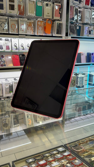 A black tablet with a pink protective case, shown from an angle inside a retail store with display cases of other accessories in the background.