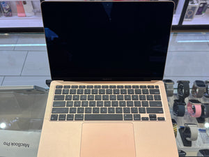 Gold MacBook Pro on a glass surface with a blurred background