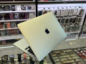 Apple laptop on display in a store with phone cases in the background