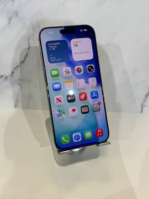 A black iPhone 14 Pro displayed on a silver metal stand against a white marble-patterned background.