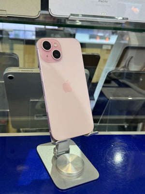 A light pink Apple iPhone shown from the back, mounted on a silver display stand inside a glass display case with other phones visible in the background.