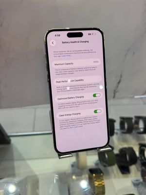 A black smartphone displayed on a stand, showing the Settings app screen for Battery Health & Charging in a store setting.
