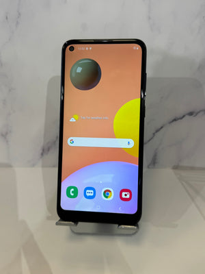 A black smartphone with a large front camera lens and a colorful home screen, displayed on a small stand against a light marble-patterned background.