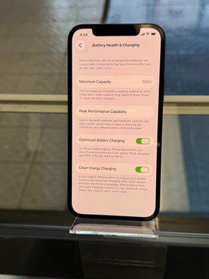 Smartphone displaying battery health and charging settings on a stand with a blurred background