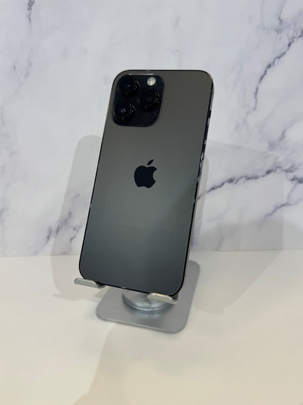 A dark gray Apple iPhone Pro shown from the back, resting on a clear stand against a white marble-patterned background.
