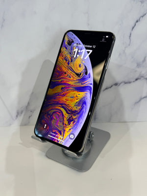 A dark colored device with a colorful screen displayed on a metal stand against a white background. 