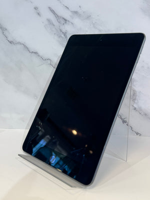 A black tablet device standing upright on a clear acrylic display stand against a white marble-patterned background.