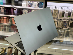 Silver Apple laptop on display in a store with phone cases in the background