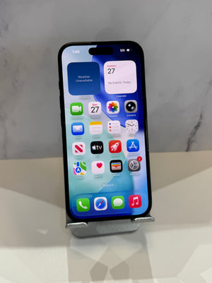 A black iPhone with its screen on, resting on a silver metal stand on a white reflective surface against a gray marble-patterned background.