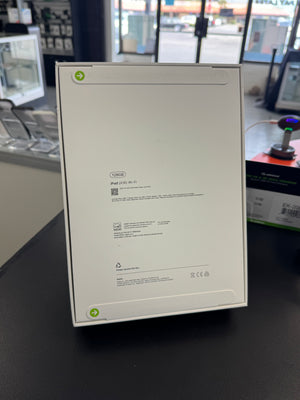 The back of a box, showing product specifications, a QR code, and recycling information, standing on a black counter in a retail store.