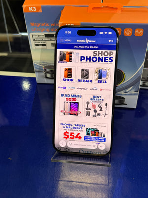 Smartphone displaying a shopping app with a phone store interface, placed on a reflective surface with a blurred background.