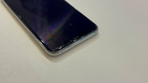 A close-up shot of a smartphone with a black screen and a silver metallic bumper, resting on a plain off-white surface.