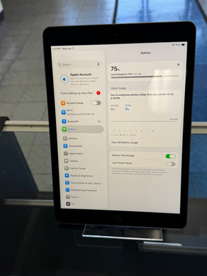Tablet displaying battery settings on a stand with a blurred background