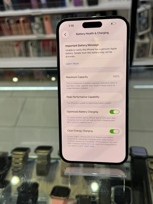 Smartphone displaying battery health and charging information on a reflective surface.