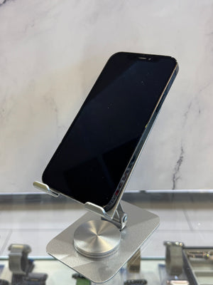 A silver metal magnetic phone stand holding a black smartphone, set against a white marble-patterned background.