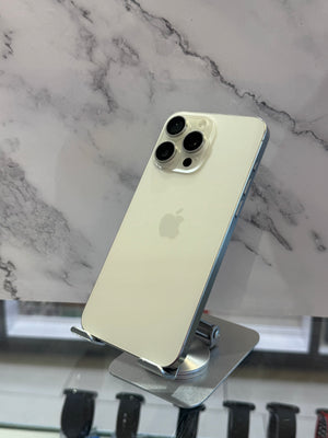 An Apple iPhone with a light gold back and silver camera module, displayed on a metal stand against a white and gray marble-patterned background.