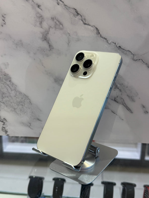 An Apple iPhone with a light gold back and silver camera module, displayed on a metal stand against a white and gray marble-patterned background.