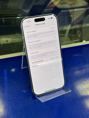 A smartphone displayed on a clear stand on a glossy blue surface, showing the Settings screen with battery-related options.