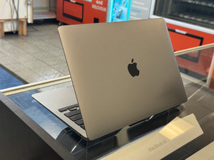 Silver MacBook Air on a reflective surface with a blurred background
