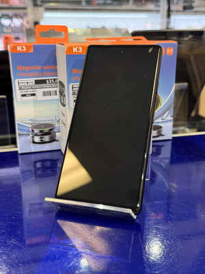 Black smartphone on a blue surface with K3 packaging in the background