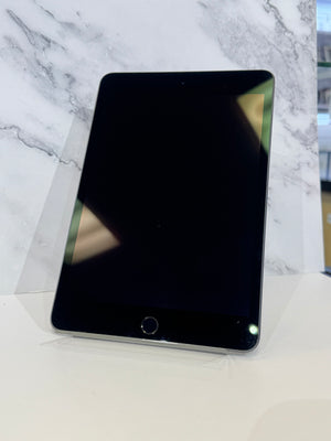 A black tablet with a black bezel and home button, standing upright on a clear display stand against a white marble-patterned background.