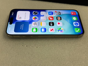 A black iPhone with its screen turned on, displaying the home screen with various colorful app icons, resting on a textured beige surface.