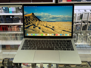 Laptop displaying a desert landscape on a glass table with a store shelf in the background