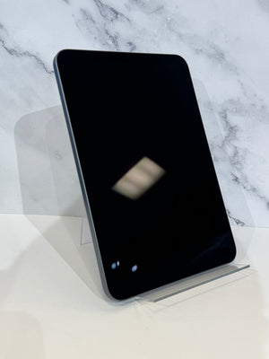 A tablet with rounded corners displayed upright on a clear acrylic stand against a white marble-patterned background.