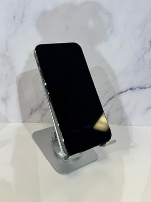 A black smartphone displayed upright on a metallic silver stand against a white marble-patterned background.