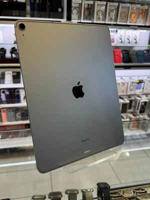 The back of a silver iPad showing the Apple logo, standing on a clear acrylic stand in a retail store setting