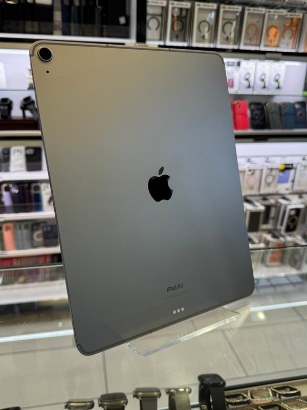 The back of a silver iPad showing the Apple logo, standing on a clear acrylic stand in a retail store setting