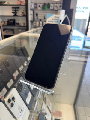 A black smartphone with a glossy screen, displayed on a clear acrylic stand inside a retail store glass case.