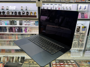 Black laptop on display in a store with shelves of electronic items in the background
