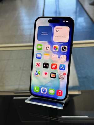 Smartphone with app icons displayed on a metallic stand against a reflective surface