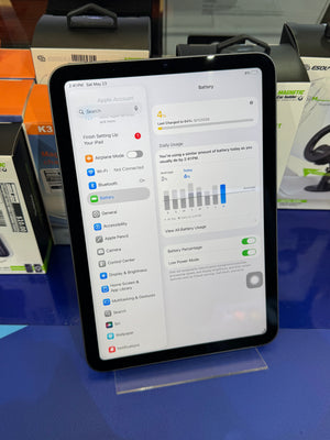 Tablet displaying a settings menu on a blue surface with packaging in the background