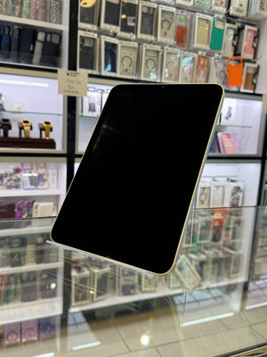 Black tablet held up in front of a display case with various items.