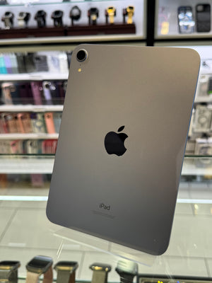 Back view of an iPad with Apple logo on a glass surface in a store setting.