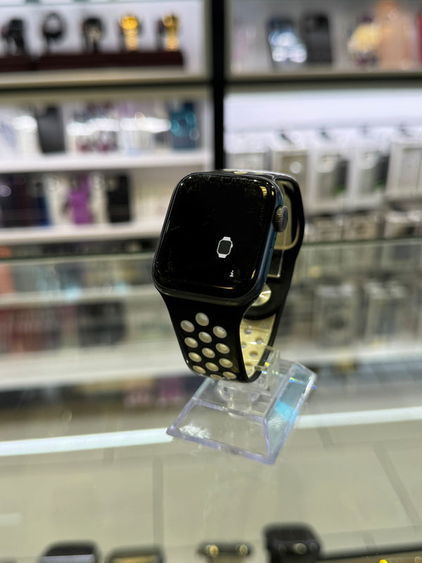 Black smartwatch on a clear stand with a blurred store shelf in the background