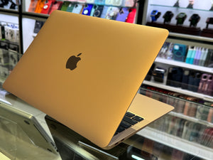 Yellow laptop with Apple logo on a glass surface in a store setting