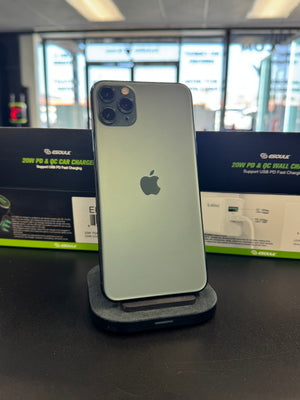 A silver Apple iPhone stands upright on a charging dock in a retail or showroom setting, with ESOUK power adapter boxes visible in the background.