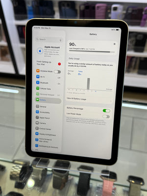 iPad displaying battery settings on a blurred store background