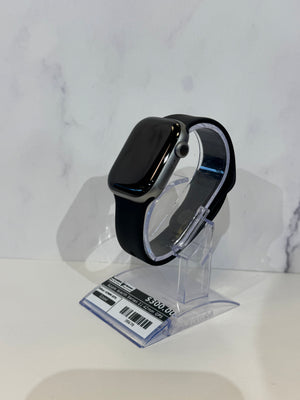 Black apple watch Series 11 42mm with a black band displayed on a plastic stand against a white marble patterned background. 