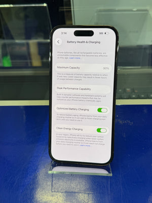 Smartphone displaying battery health and charging settings on a reflective surface