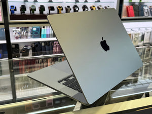 Silver laptop with Apple logo on a display stand in a store.
