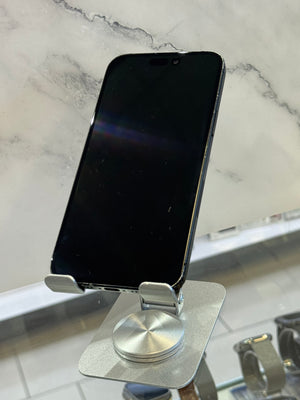 A silver magnetic phone mount with a square suction-style base and a black smartphone inserted, photographed on a light marble-like surface.
