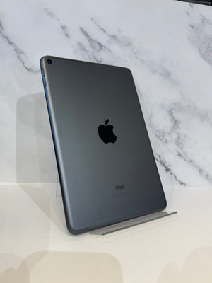 A dark gray Apple iPad standing upright on a clear display stand against a white marble-patterned background.