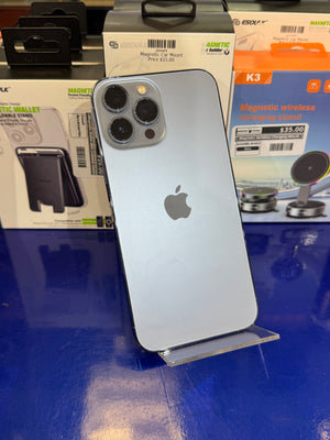 Silver iPhone with Apple logo on a blue surface with magnetic charging stand packaging in the background.