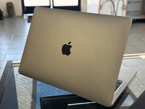 Apple laptop on a reflective surface with a blurred background