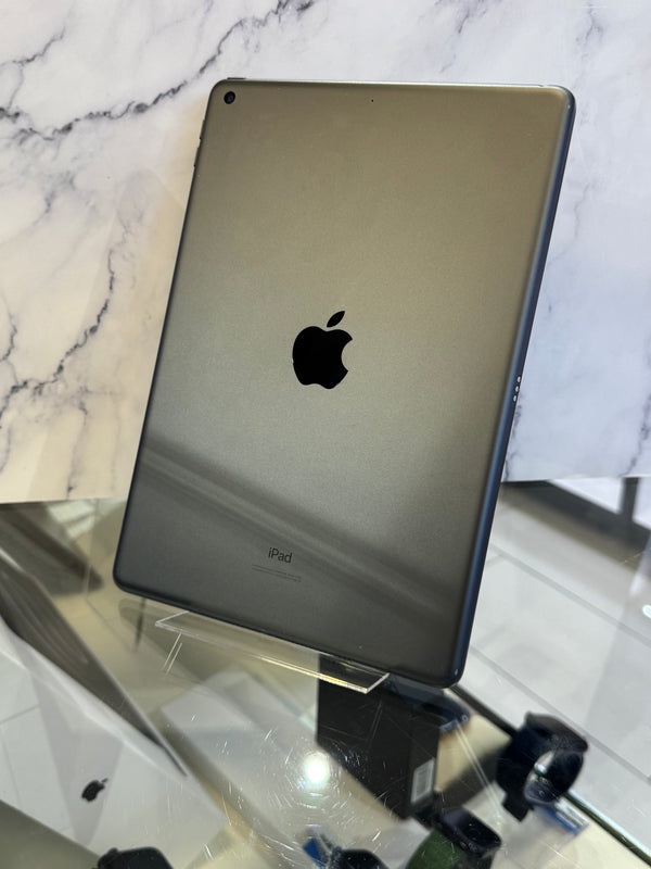 An Apple iPad with a dark metallic gray finish, shown from the back resting on a clear display stand.
